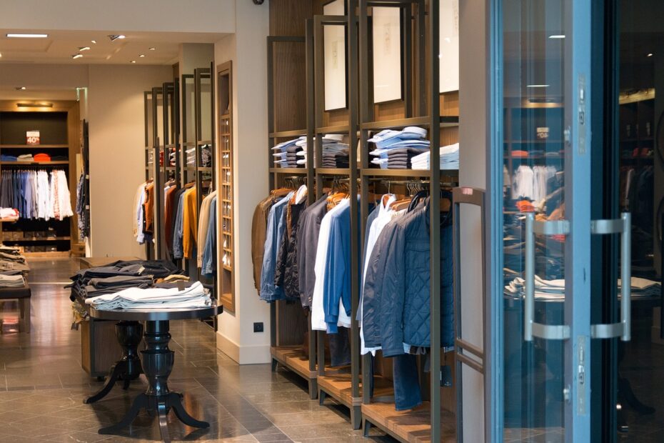 Interno di un negozio di abbigliamento con diversi abiti e giacche appesi